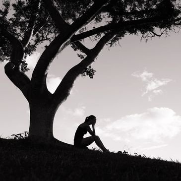 Lady sitting under a tree hoping for More Than Enough.