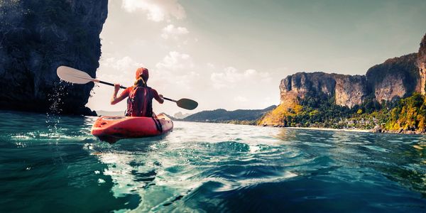 Low angle shot of kayaker paddling away on the ocean on calm day. Wish it was me - goals!