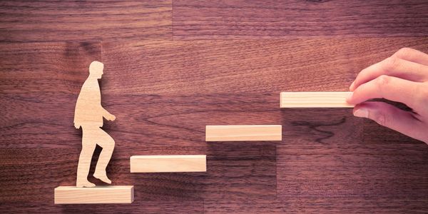 A wooden figure climbing a set of stairs