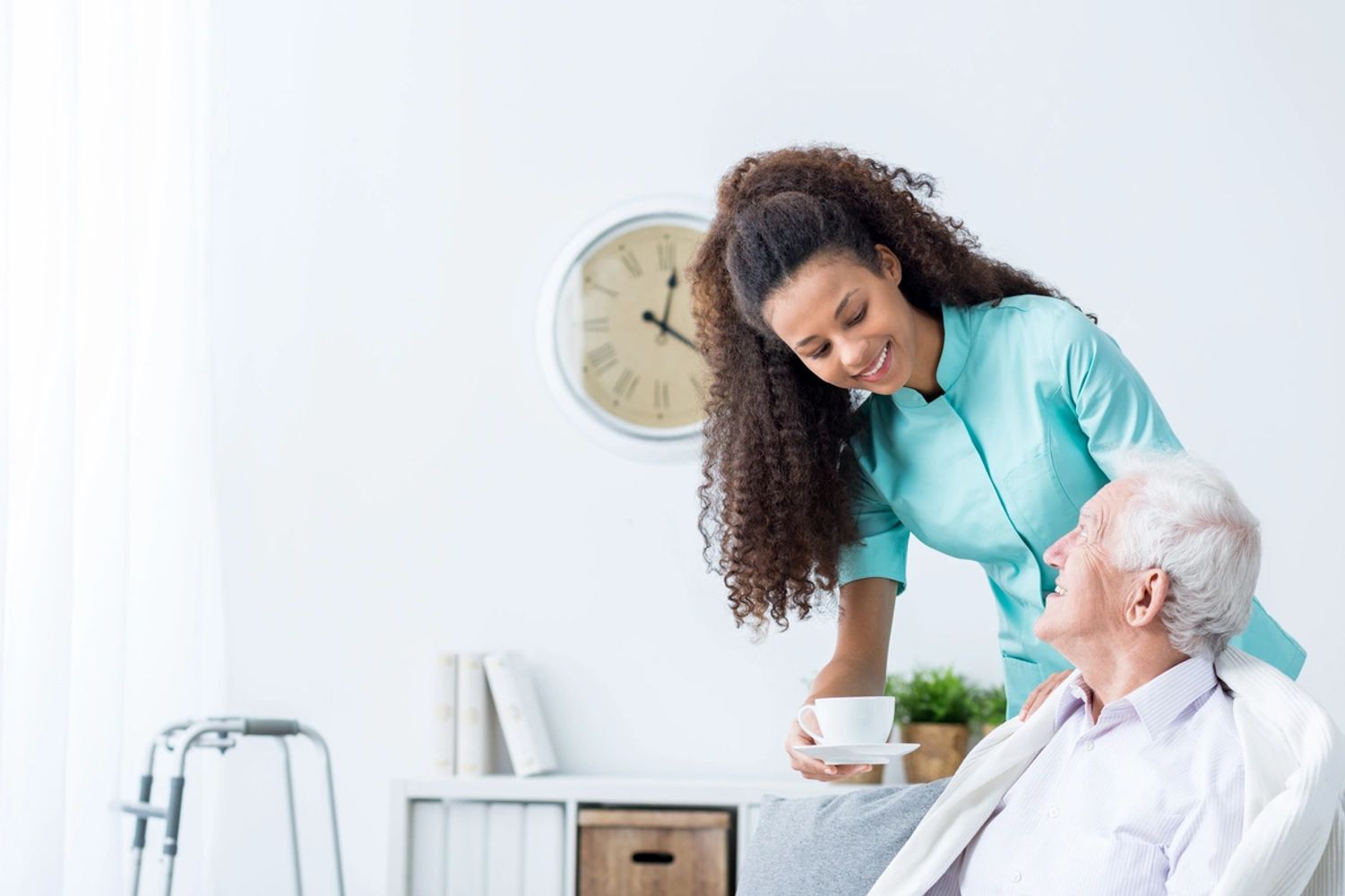 Caregiver offering tea to an older man in his home