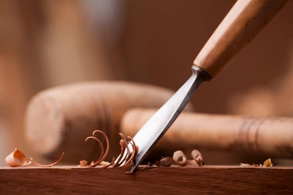 Wood carving tool shaving wood with mallet in background.
