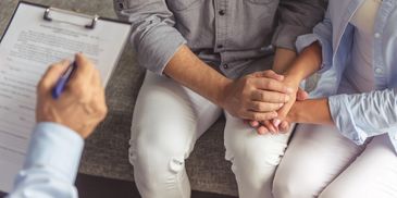 A couple holding hands while talking to a doctor