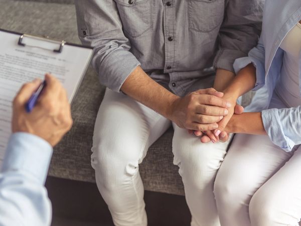 Couple holding hands during a counseling session with a therapist.
