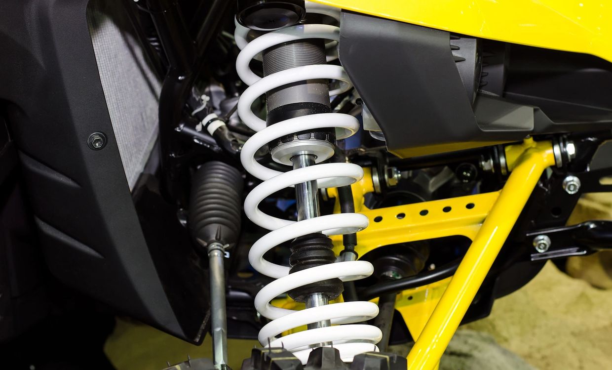 Close-up of a vehicle suspension system with white coil springs and yellow frame.