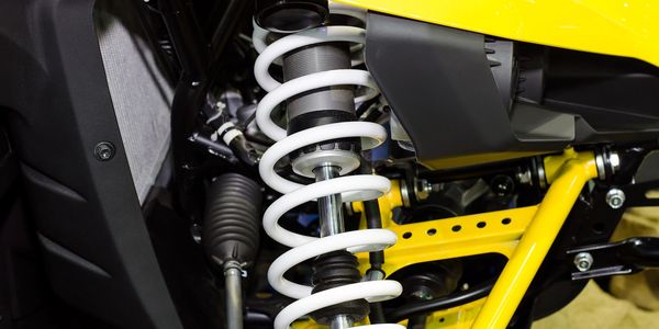 Close-up of a white coil spring suspension on a yellow vehicle.