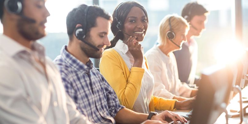 A diverse team of call center agents working with headsets and computers.