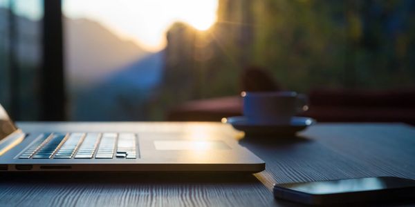 Laptop on outside table in front of a sunset