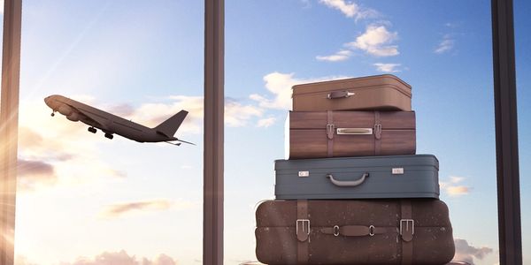 Airplane taking off. Vintage suitcases stacked on top of each other in airport by terminal window.