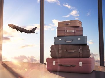 Stack of suitcases with a plane taking off in the background.