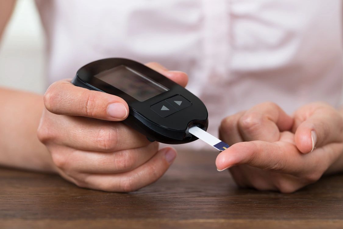 Person checking blood sugar levels with a glucometer.