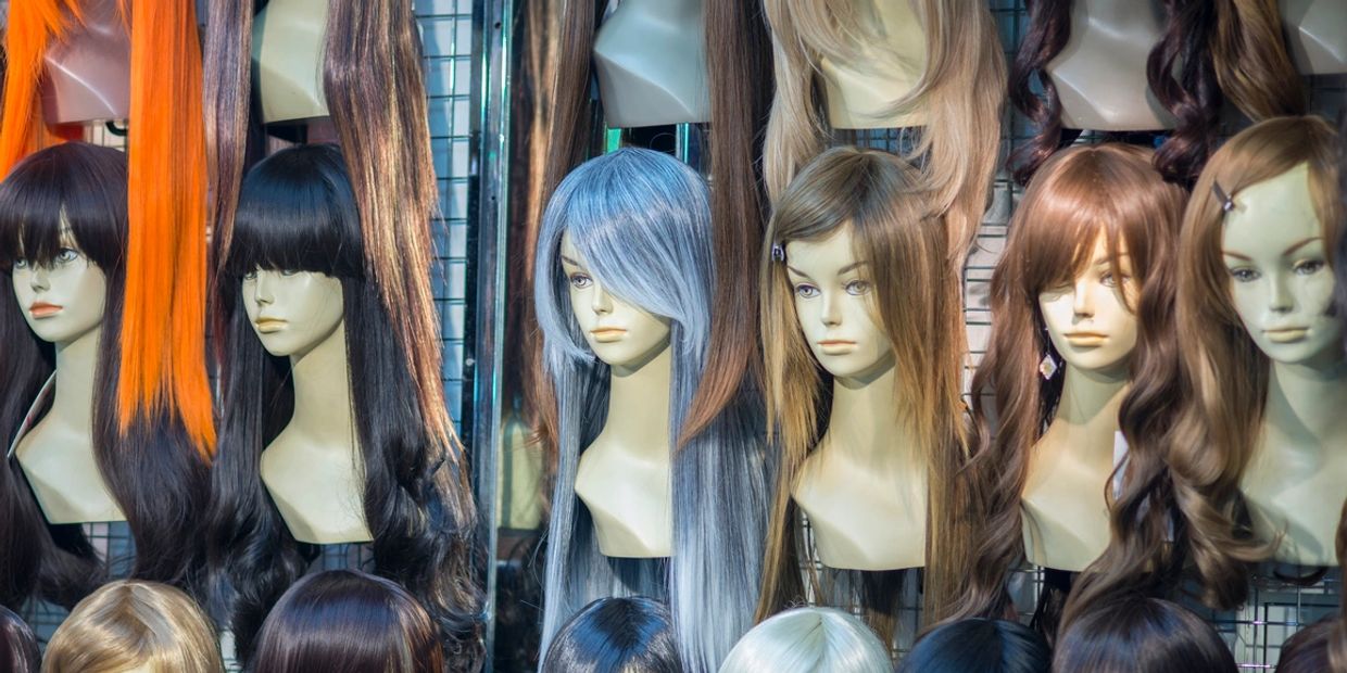 Mannequin heads displaying various colorful wigs in a shop.