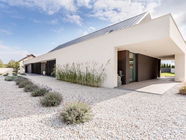 Modern white house with gravel landscaping and tall grasses.