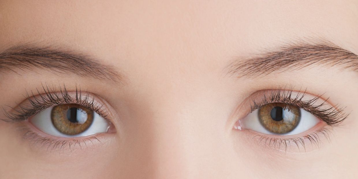 Close-up of hazel eyes with long eyelashes and well-groomed eyebrows.