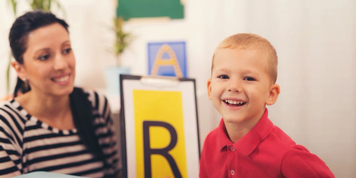Happy boy with teacher and letter cards.