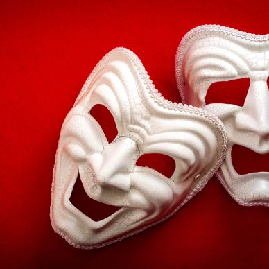 Two white comedy and tragedy masks on a red background.