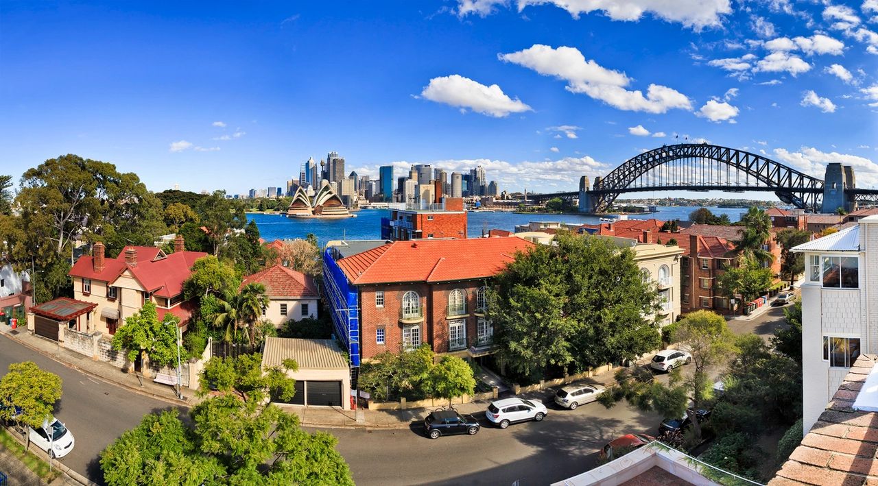 A bridge provides a path over the waterway with the nearby city block with homes and parked cars shown beneath.