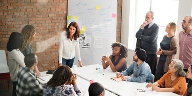 Woman standing facilitating a workshop meeting with a group of people