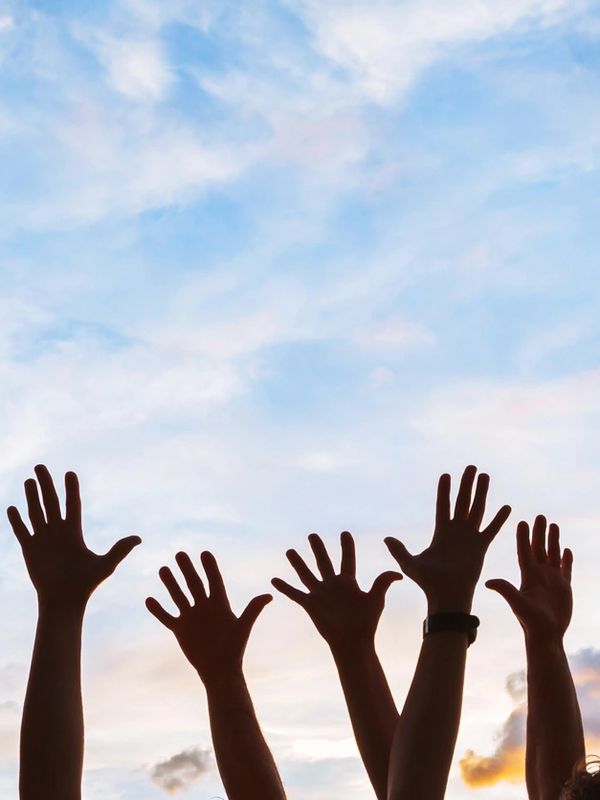 Image of people's hands raising up into a blue sky.