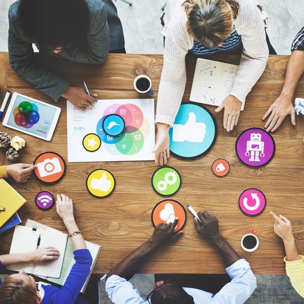 Diverse team collaborating with colorful icons and charts on a wooden table.