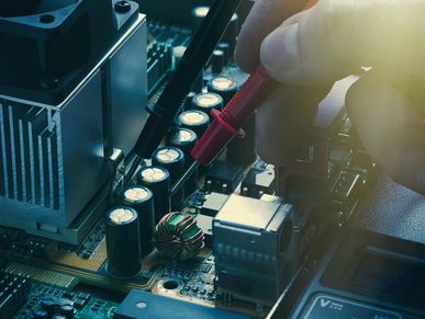 Testing a computer motherboard using multimeter probes.