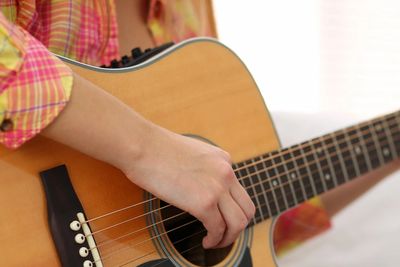 Person playing an acoustic guitar with focus on the hand and strings.