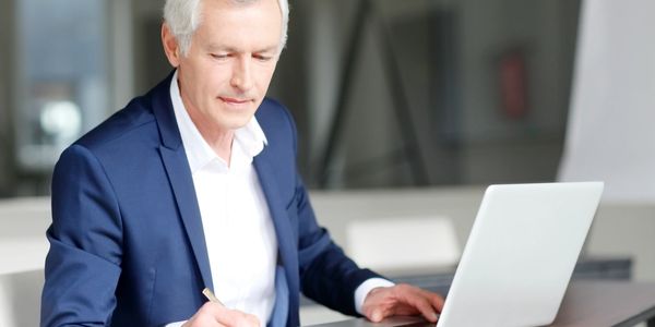 a financial advisor sitting in front of a laptop working on a report. 