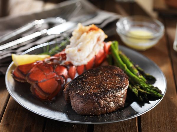 Grilled steak and lobster tail with asparagus on a plate.
