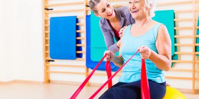 A senior is guided through her resistance band exercises by her Physiotherapist.