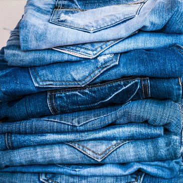 Stack of folded blue denim jeans with visible pockets.