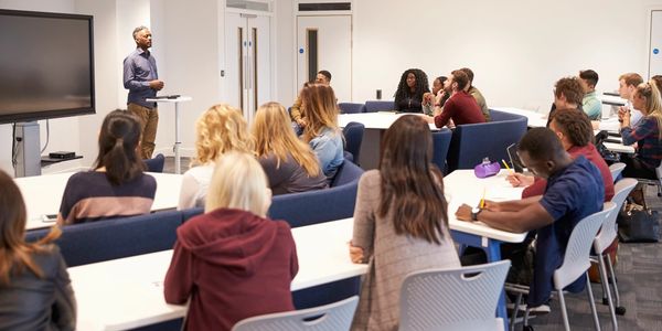 A teacher giving a lecture to a diverse group of students in a modern classroom.