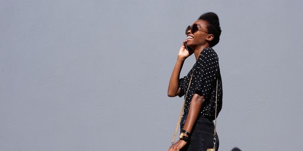 Black woman smiling and talking on her phone. 