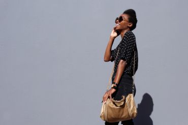 Stylish woman smiling against gray wall.