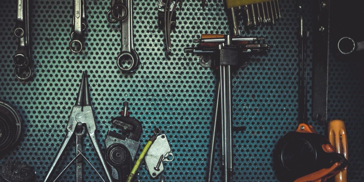 Various tools hanging on a perforated board.