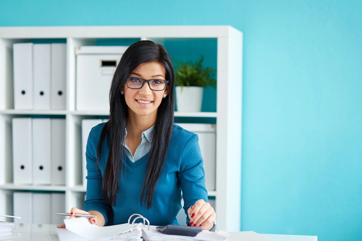 a girl in a blue top is holding a pen 