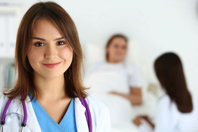 Smiling female doctor with stethoscope in hospital room.