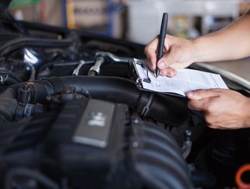 Mechanic with a notepad for recording mot details 