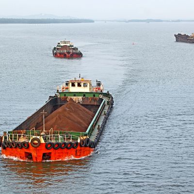 Cargo ships transporting bulk material on a calm waterway.