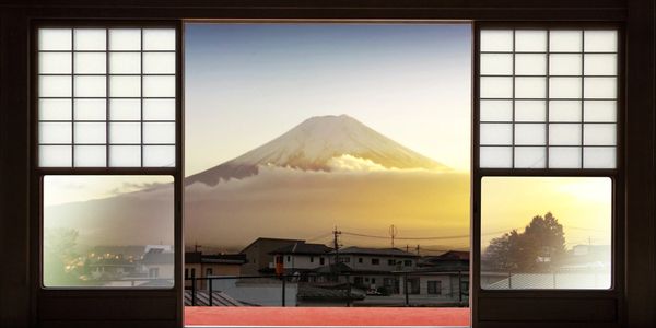 View of Mount Fuji at sunrise through traditional Japanese shoji doors.