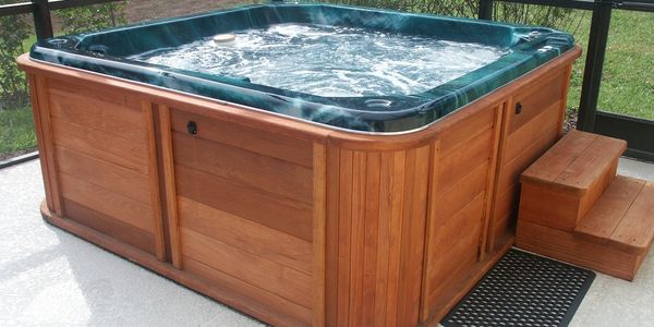 Wooden hot tub filled with foamy water on a patio.