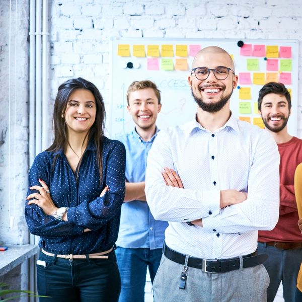 Group of five confident coworkers smiling, arms crossed.