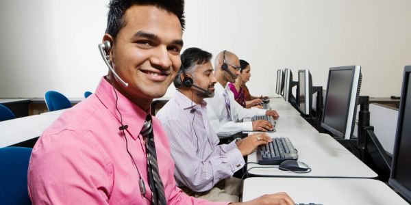 Man in front of computer with headset on smiling 