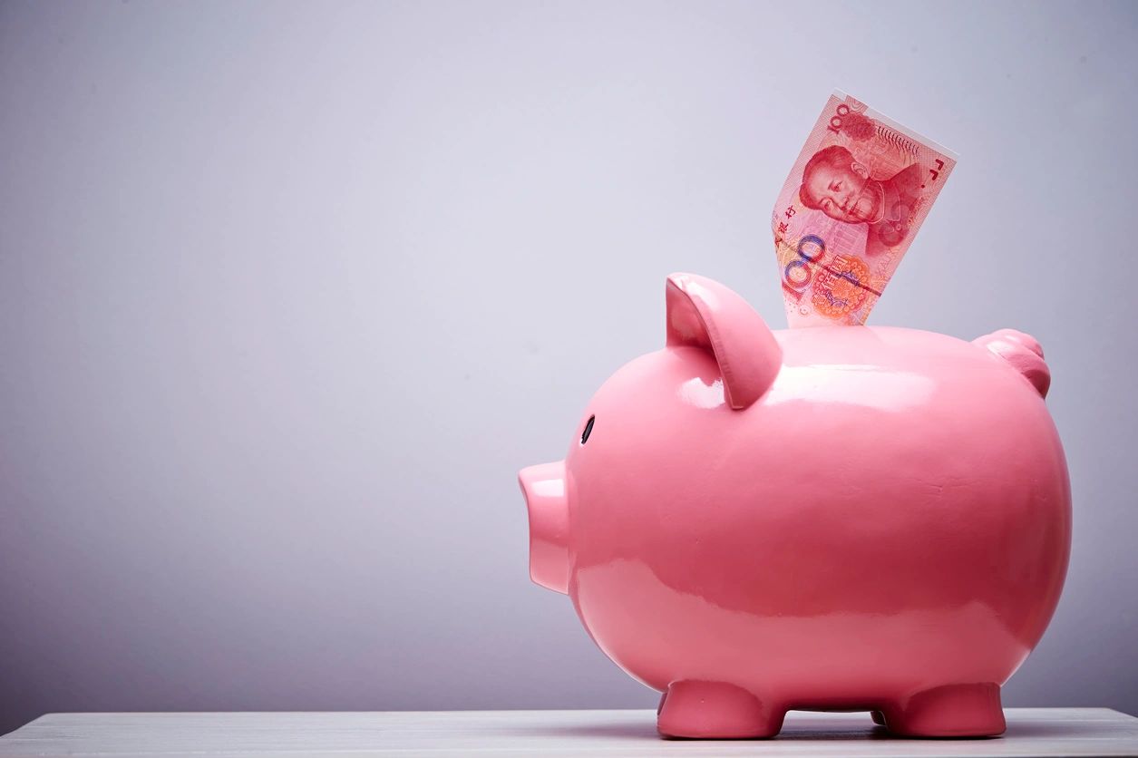 Pink piggy bank with a 100 yuan note inserted.
