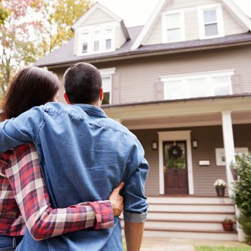 Family embracing in front of  their new home after closing their mortgage. 