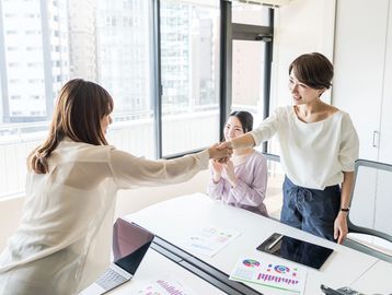 Two women wearing white and shaking hands