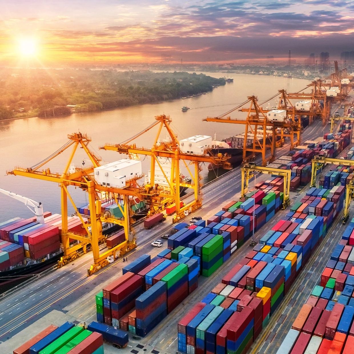 A busy port with cargo ships and containers at sunset.