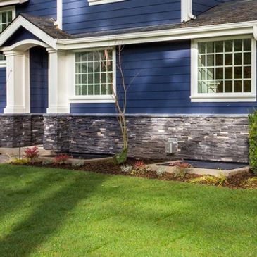 Large blue two-story house with a porch and well-maintained lawn.