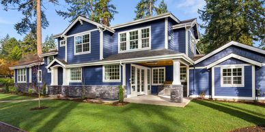 A beautiful two-story blue house with white trim and a green lawn.