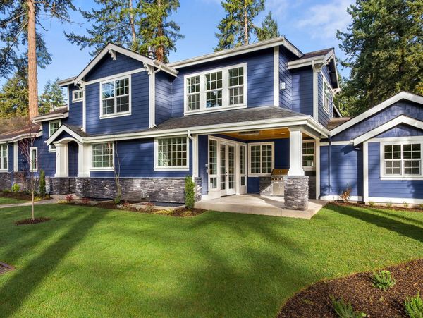 A large blue house with a porch sitting on the grass.