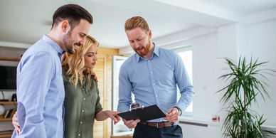 A couple reviews some options on a clipboard with their realtor.