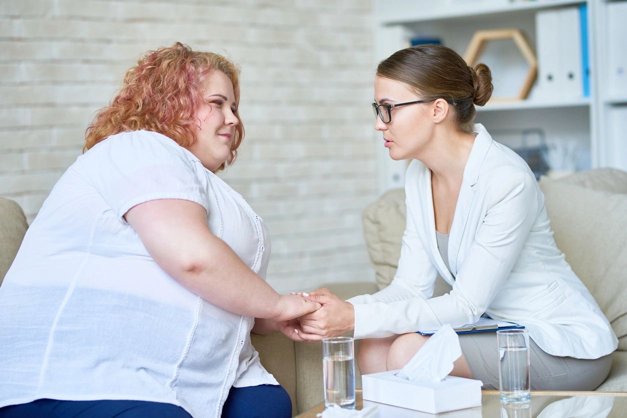 One white female therapist holding the hands of her white red-haired female client